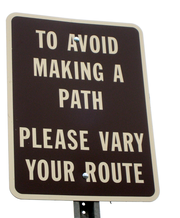 Ein Schild an einem Pfahl vor einem weißen Hintergrund trägt die Aufschrift "Um einen Pfad zu vermeiden - Bitte variieren Sie Ihre Route."