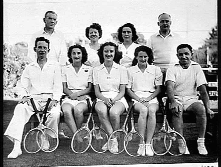 Ein Schwarz-Weiß-Foto von Menschen auf einer Bank sitzend, die lächeln und Tennisrackets halten, mit Bäumen und einem klaren Himmel im Hintergrund und dem Text "Tennis Hall of Fame" unten.