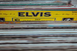Ein ordentlicher Stapel von Elvis-Presley-Platten auf einem Tisch, mit sichtbaren Titeln und einem unscharfen Hintergrund.