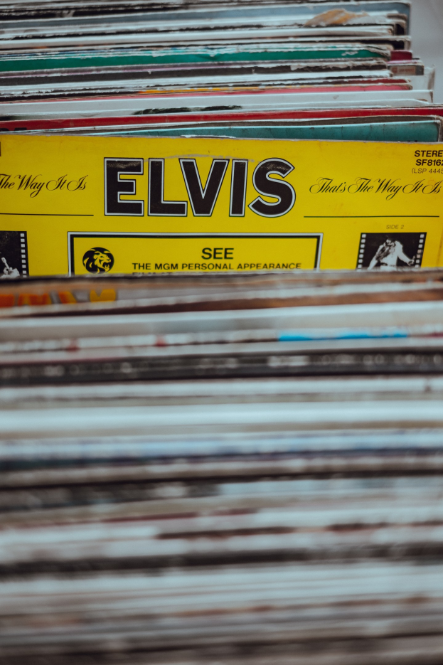 Ein ordentlicher Stapel von Elvis-Presley-Platten auf einem Tisch, mit sichtbaren Titeln und einem unscharfen Hintergrund.