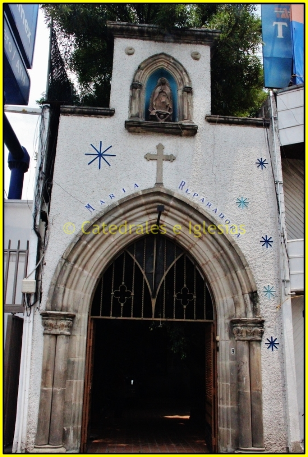 Eine Kirche von vorne mit einem Baum und Bannern öber dem Dach.