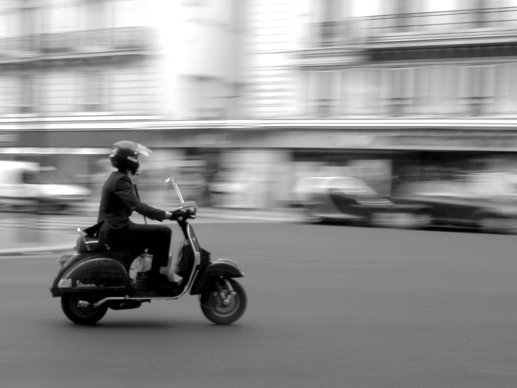 Eine Person fährt mit einem Roller auf der Straße.