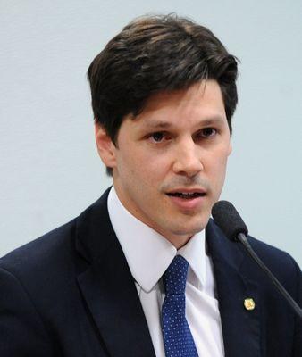 Ein Mann im Anzug und mit Krawatte spricht in ein Mikrofon, wahrscheinlich um die Genehmigung eines Gesetzes durch die Regierung zu kommentieren.