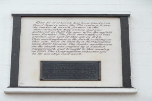 Plaque auf einer Gebäudewand mit der Aufschrift "National Register of Historic Places" in fetter Schrift, umgeben von einem dekorativen Rahmen, auf dunklem Material montiert.