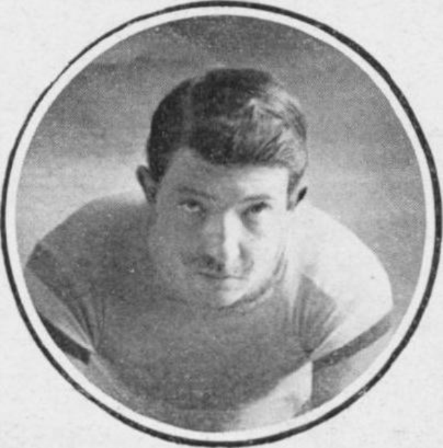 Schwarzes und weißes Foto eines Mannes in einem Fußballtrikot mit ernstem Gesichtsausdruck, dunkle kurze Haare, konzentriert auf einen fernen Punkt.