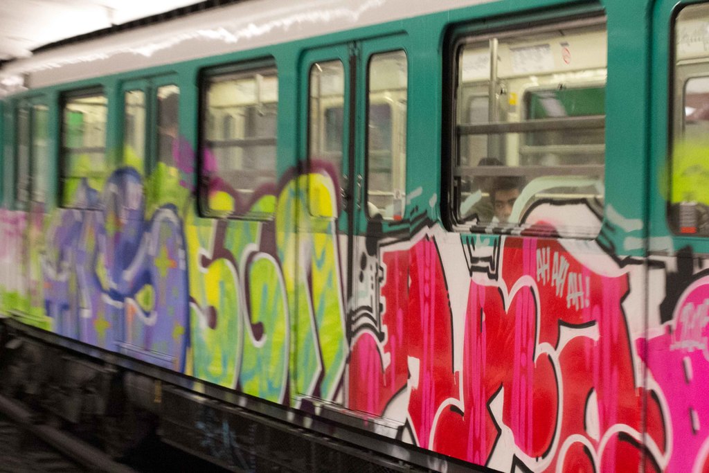 Ein Zug auf den Eisenbahnschienen mit zwei Personen darin und Graffiti an seiner Außenseite.