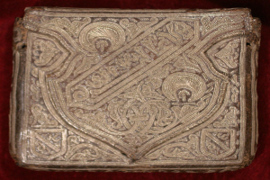 Ein goldbedecktes Buch mit detaillierten Designs auf einem roten Samt-Hintergrund.