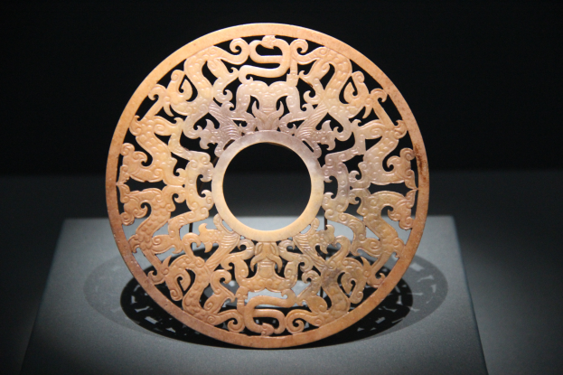 Ein chinesischer geschnitzter Jade-Teller in einem Museum ausgestellt, mit detaillierten Oberflächenverzierungen und dunklem Hintergrund.