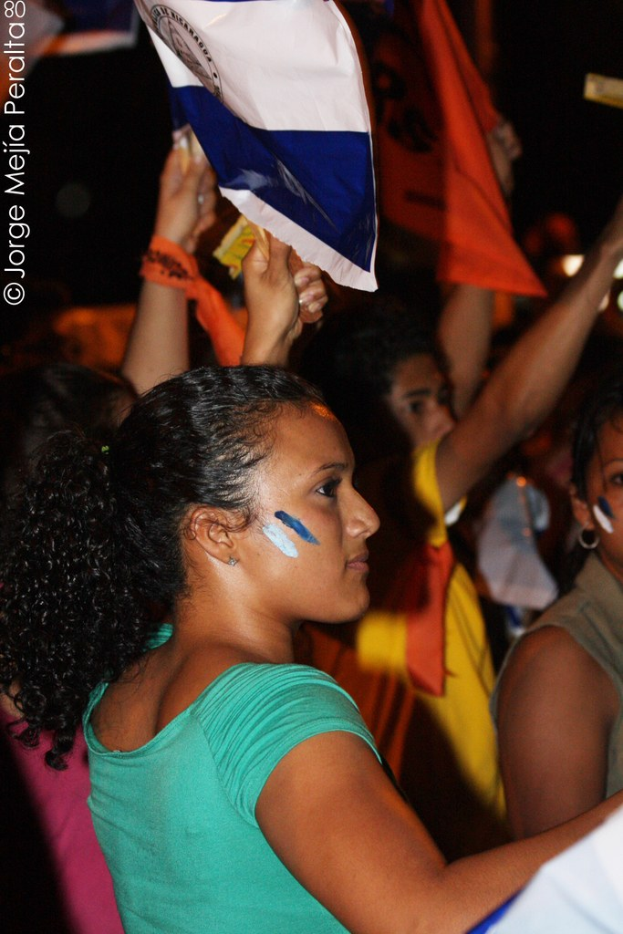Frauen in grünen T-Shirts halten weißen Stoff, während sie auf einer Demonstration stehen, mit mehreren anderen Mädchen im Hintergrund.