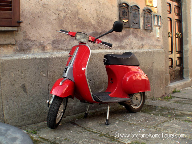 Ein roter E-Scooter steht vor einem Haus mit Tür und Fenstern auf einer Straße mit Text am unteren Rand.