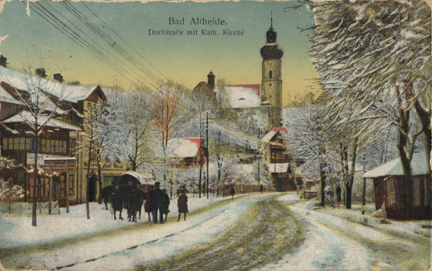 Eine alte Postkarte zeigt eine verschneite Straße in Bad Alteide, Deutschland, mit Menschen, die spazieren gehen, gesäumt von Bäumen, Pfählen und Gebäuden und einem sichtbaren Himmel im Hintergrund, mit Text oben.