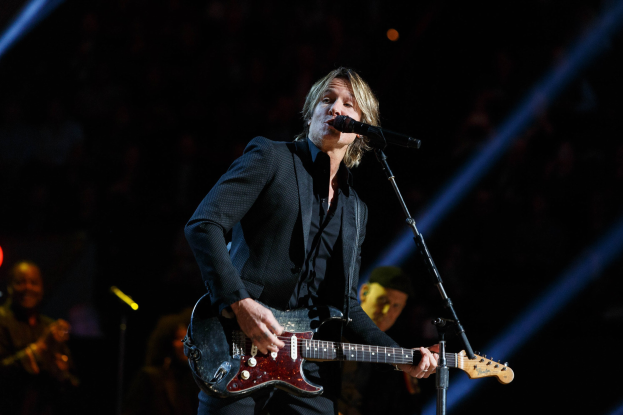 Keith Urban performs auf der Bühne im Joint im Hard Rock Hotel & Casino in Las Vegas, spielt Gitarre mit einem Mikrofon und Bandmitgliedern im Hintergrund in einer schwach beleuchteten Umgebung.