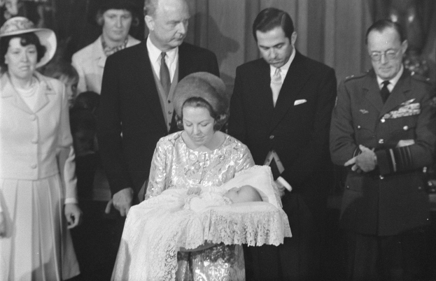 Königin Elizabeth II hält ihren neugeborenen Sohn Prinz Philip im Arm, während Prinz Philip, Herzog von Edinburgh, neben ihr in einem Anzug und einer Krawatte steht, mit Vorhängen im Hintergrund.