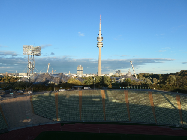 Olympiastadion in Berlin, Deutschland, mit dem fernsehübertragbaren Turm im Hintergrund, umgeben von Bäumen, Gebäuden und Lichtern.