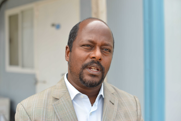 Ein Mann im Anzug und Krawatte steht vor einem Gebäude mit einer Tür und einem Fenster und sieht besorgt aus, wahrscheinlich wegen einer lebenslangen Haftstrafe.