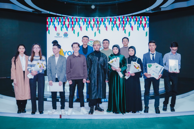 Eine Gruppe von Menschen auf einer Bühne, jeder hält einen Blumenstrauß und Urkunden in der Hand, im Hintergrund ein Schild mit der Aufschrift "Youth Solar Awards 2019"