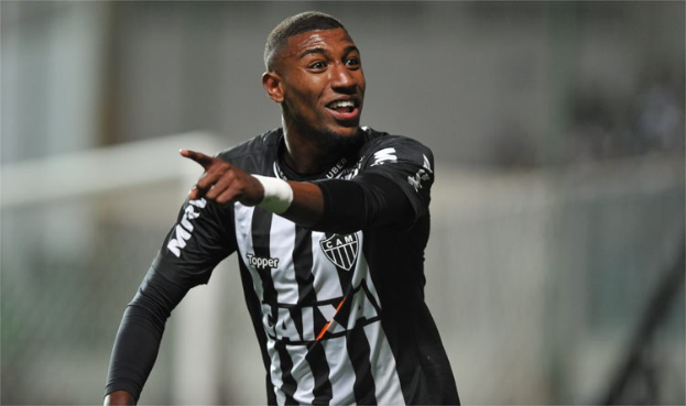 Ein Fußballspieler in einem schwarz-weißen gestreiften Trikot feiert mit einem Lächeln nach einem Tor