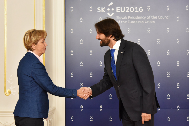 Bundeskanzlerin Angela Merkel und Bundespräsident Joachim Gauck geben sich die Hand vor einem "EU-Gipfel"-Plakat, beide lächeln.