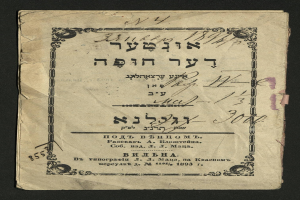 Altes Buch mit hebräischer Schrift auf schwarzem Hintergrund, die sichtbare Seite liest "Jüdisches Pessach-Seder".
