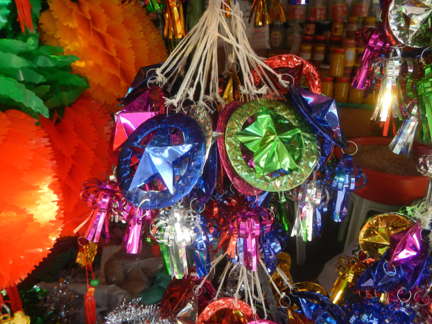 Bunte Dekorationen wie Laternen und Bänder hängen von der Decke über Regalen voller Flaschen in einer festlichen Atmosphäre.