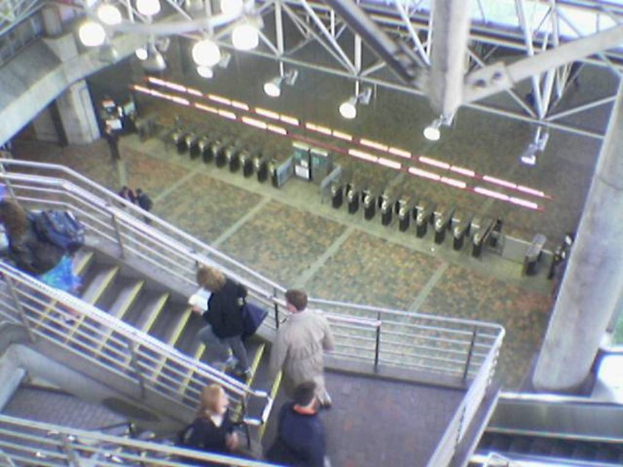 Ein Flugzeugrampen-Tor mit Personen auf der Treppe unten und Lampen und Eisenstangen oben.