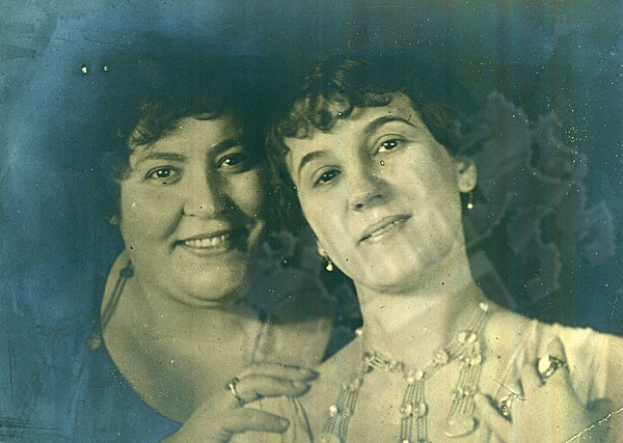 Zwei Frauen, die fröhlich in die Kamera lächeln, mit strahlenden Augen und lebendigen Gesichtern.