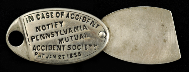 Ein Metallschild mit der Aufschrift "Im Falle eines Unfalls, benachrichtigen Sie die Pennsylvania Mutual Accident Society" vor einem schwarzen Hintergrund.