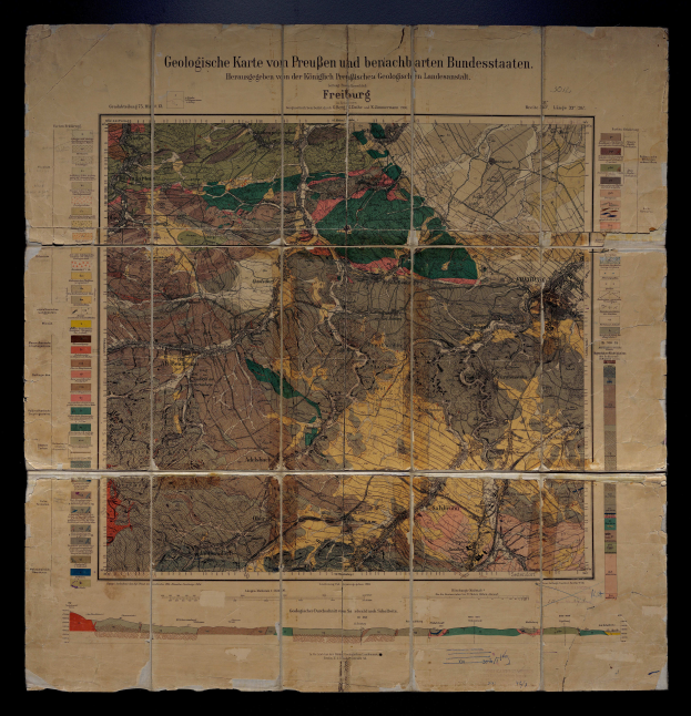 Ein altes geologisches Kartenbild von Deutschland auf einem schwarzen Hintergrund, das verschiedene geologische Merkmale wie Berge, Flüsse und Täler zeigt, mit begleitendem Text.