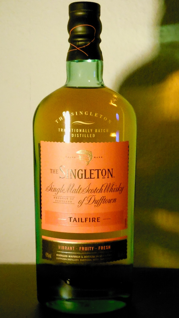 Tiefe bernsteinfarbene Flasche Singleton of Dufftown Tailfire Single Malt Scotch Whisky mit einem schwarzen Etikett, das ein Löwen- und ein Burgwappen zeigt.