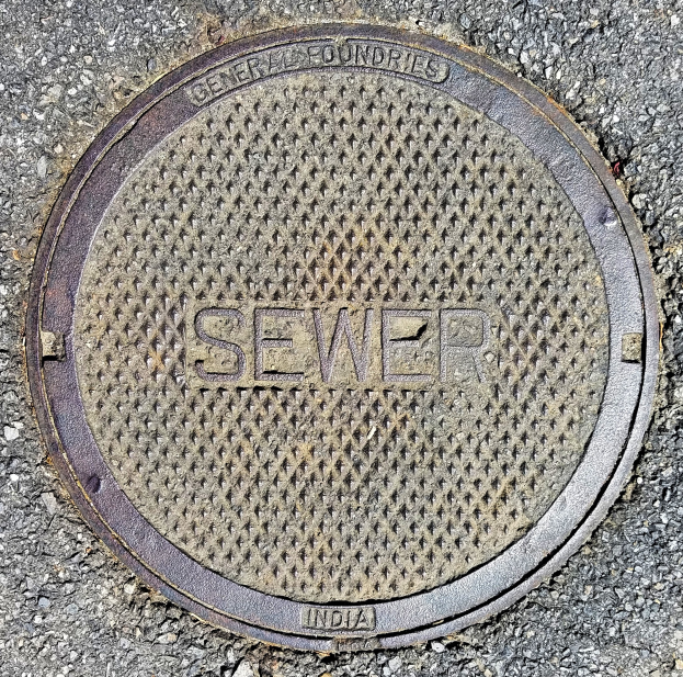 Metall-Schachtobjekt auf der Straße mit dem Wort "Kanal" geprägt.