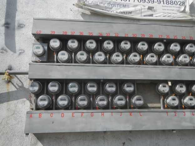 Nahaufnahme eines Elektrizitätszählers an der Seite eines Gebäudes mit einem Banner mit Text oben.