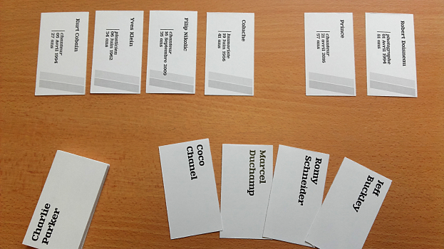 Ein Holztisch mit einem Stapel weißer Visitenkarten, auf denen jeweils Text gedruckt ist.