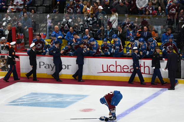 Eishockeyspieler auf dem Eis umgeben von Fans und Teammitgliedern während eines Spiels von Colorado Avalanche gegen San Jose Sharks am 24. März 2015 mit Zuschauern im Hintergrund.