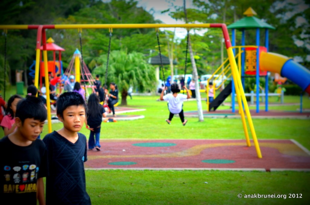 Kinder auf Spielgeräten im Park mit Bäumen im Hintergrund