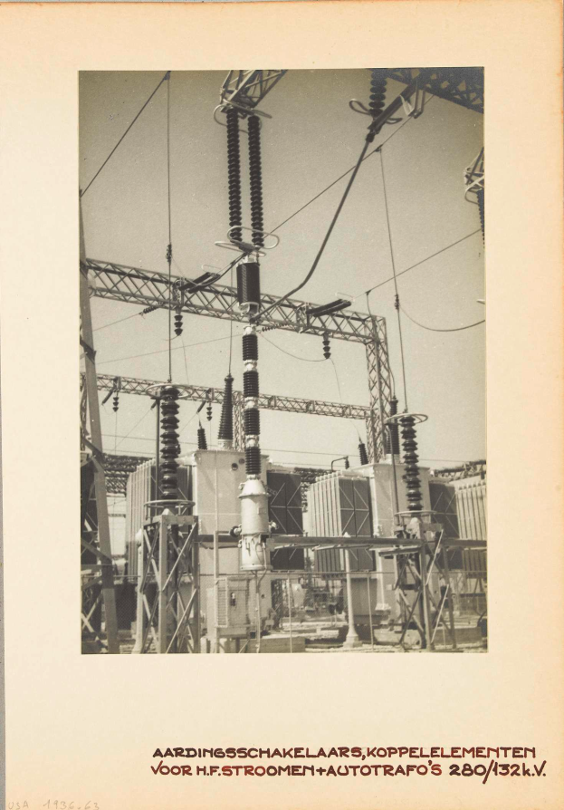 Ein altes Schwarz-Weiß-Foto einer elektrischen Umspannstation mit sichtbaren Transformatoren, Drähten und Text unten.