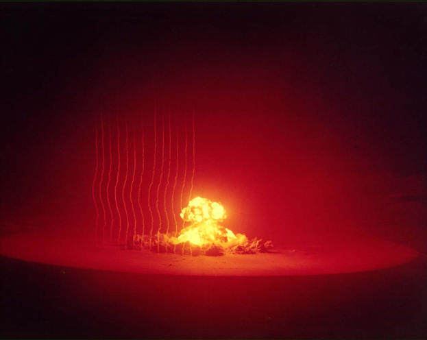 Eine Atombombe, die in einem roten Feld explodiert, mit helloranger und gelber Helligkeit, Text unten: "Atombombe".