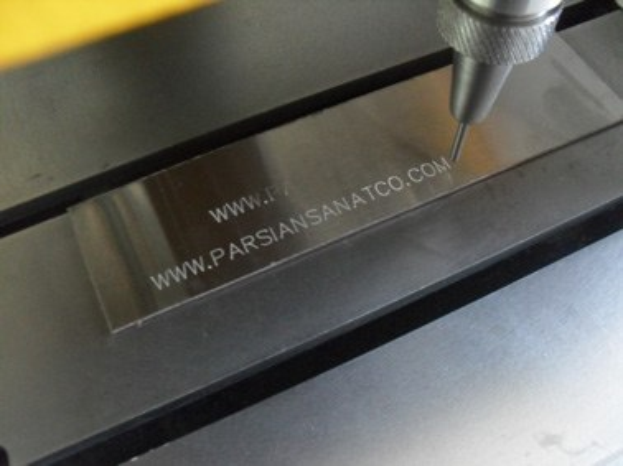 Eine CNC-Fräsmaschine fräst ein Metallstück mit eingraviertem Text.