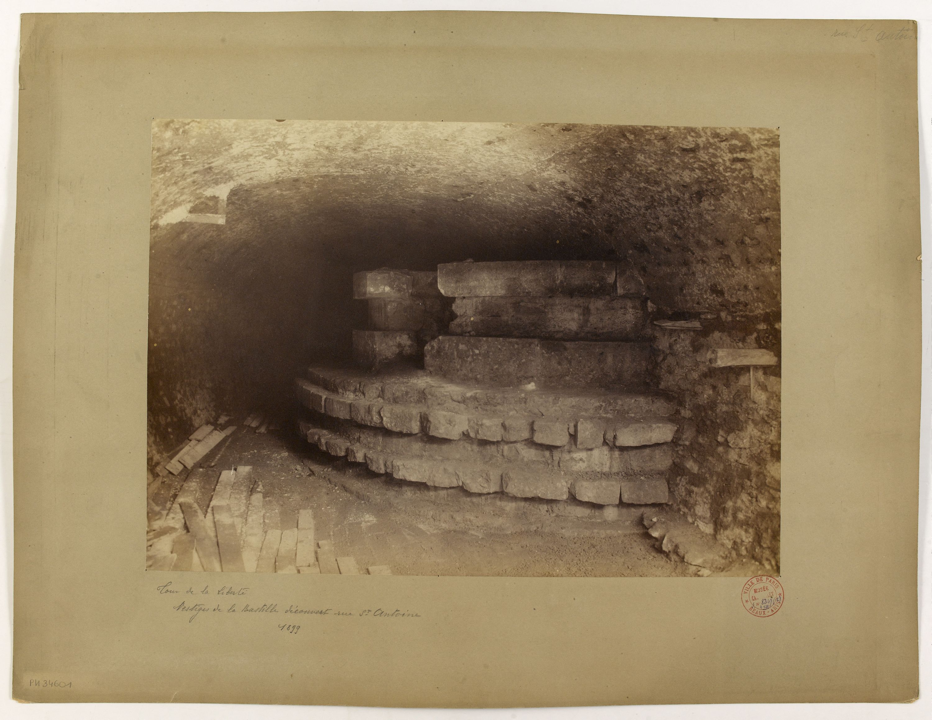 Ein altes Schwarz-Weiß-Foto eines Tunnels mit einer Treppe, die nach oben führt, mit Text unten.