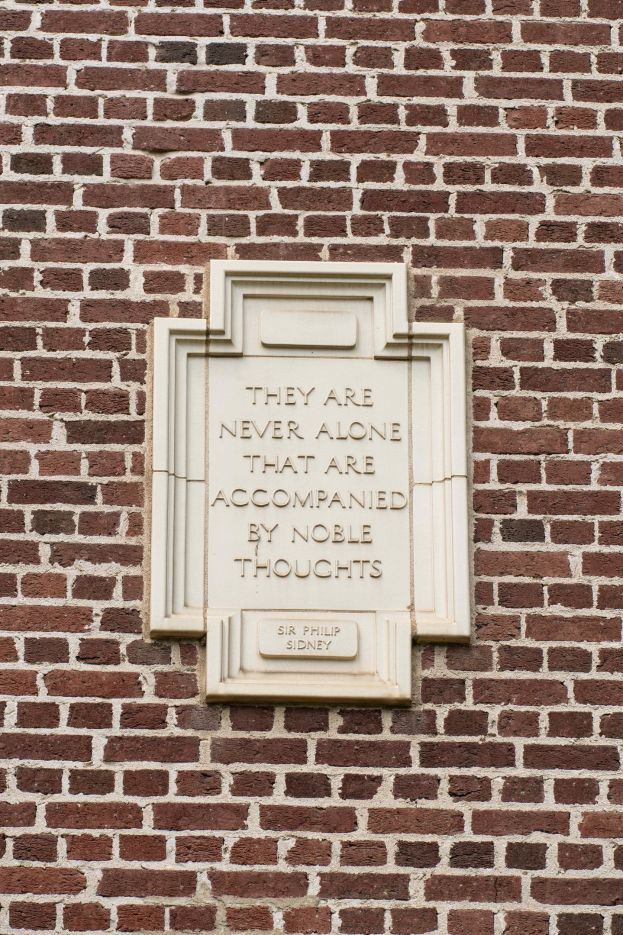 Steintafel auf einer Ziegelwand mit der Inschrift "Sie sind nie allein, die von edlen Gedanken begleitet sind."