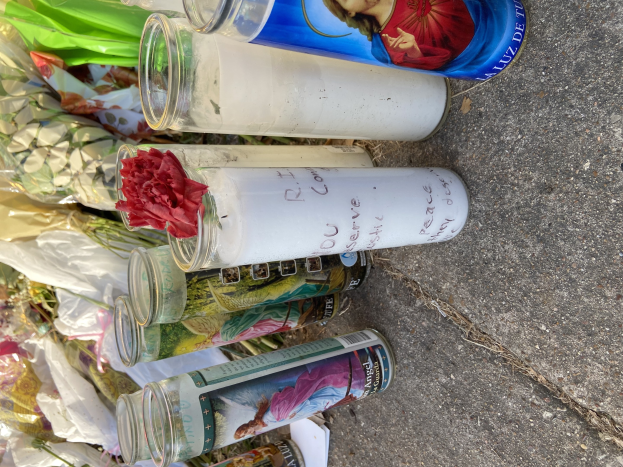 Provisorisches Denkmal mit Glasflaschen mit Bildern und Texten, einem Blumenstrauß und angezündeten Kerzen auf der Straße.