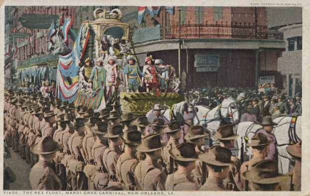 Eine alte Postkarte zeigt einen Mardi Gras-Umzug in New Orleans mit einem geschmückten Wagen, Reiter und Zuschauern am Straßenrand, mit der Aufschrift "The Rex Float, Mardi Gras Carnival, New Orleans" unten.