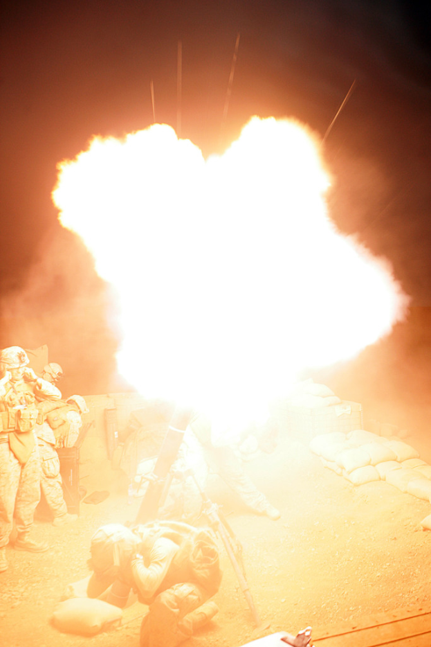 Mehrere Personen in Uniformen und Helmen befinden sich auf einem Gebiet mit einigen Taschen, die herumliegen, und ein Feuer brennt in der Mitte der Szene.
